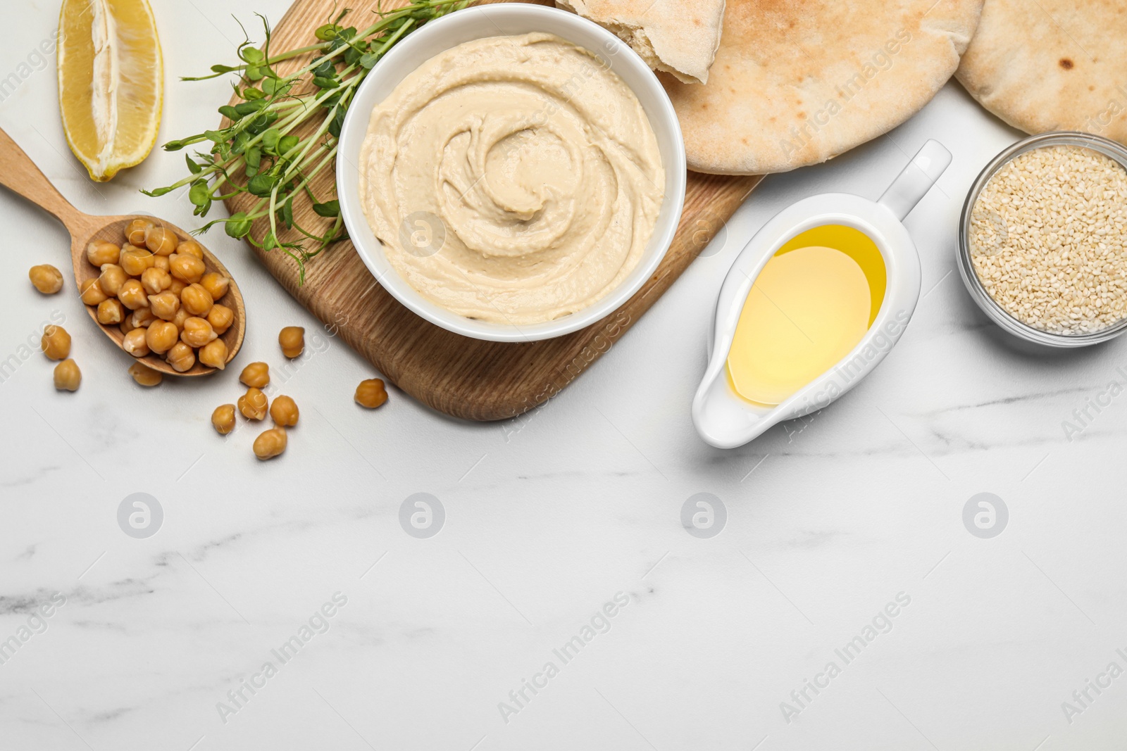 Photo of Delicious hummus and different ingredients on white marble table, flat lay. Space for text