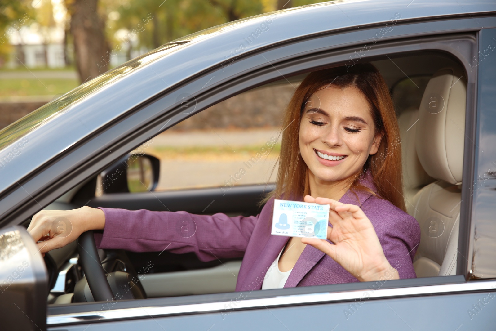 Photo of Happy woman holding driving license in car