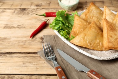 Photo of Fresh delicious crispy samosas served on wooden table, closeup. Space for text