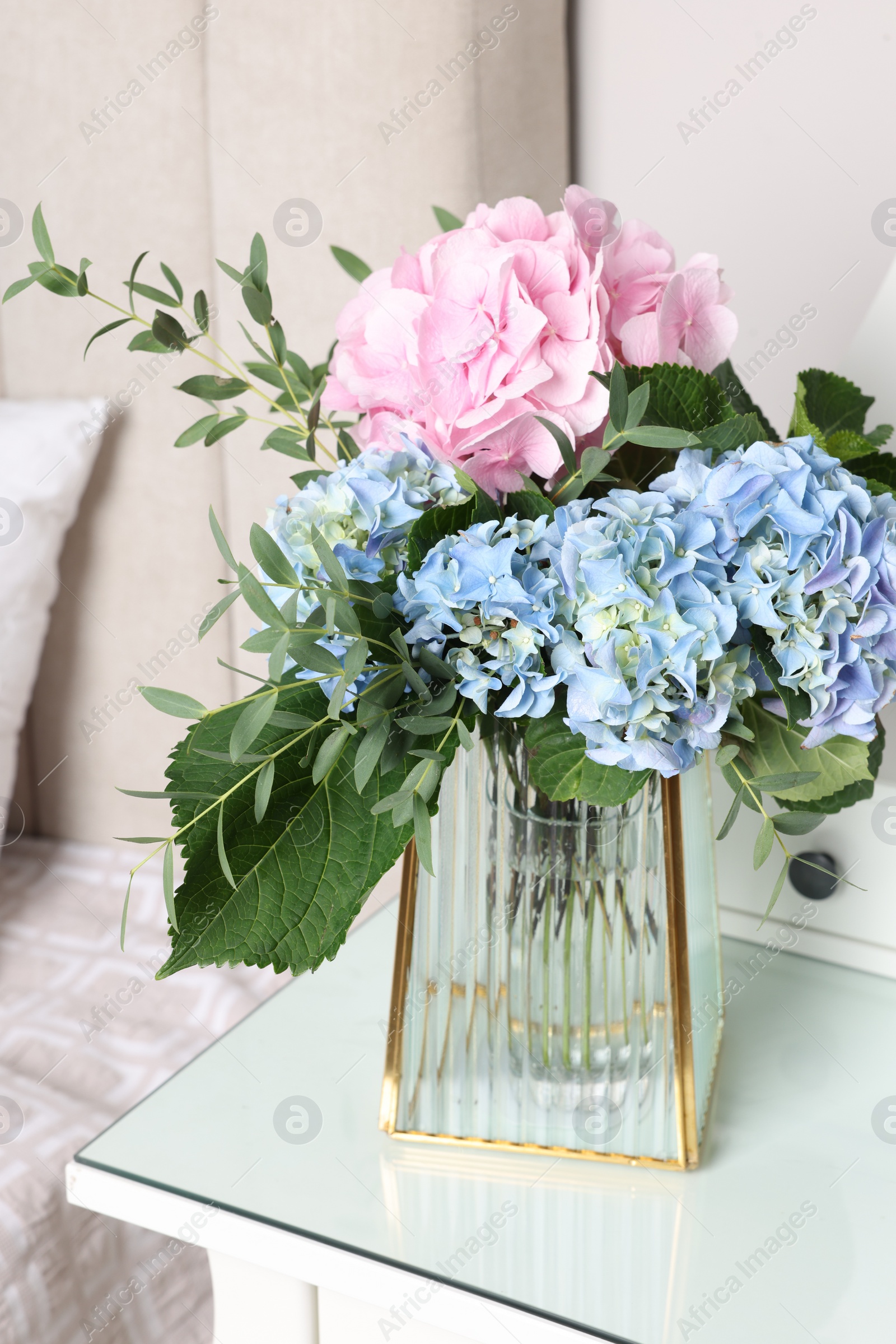 Photo of Blooming hortensia flowers in vase on white table indoors