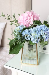 Blooming hortensia flowers in vase on white table indoors