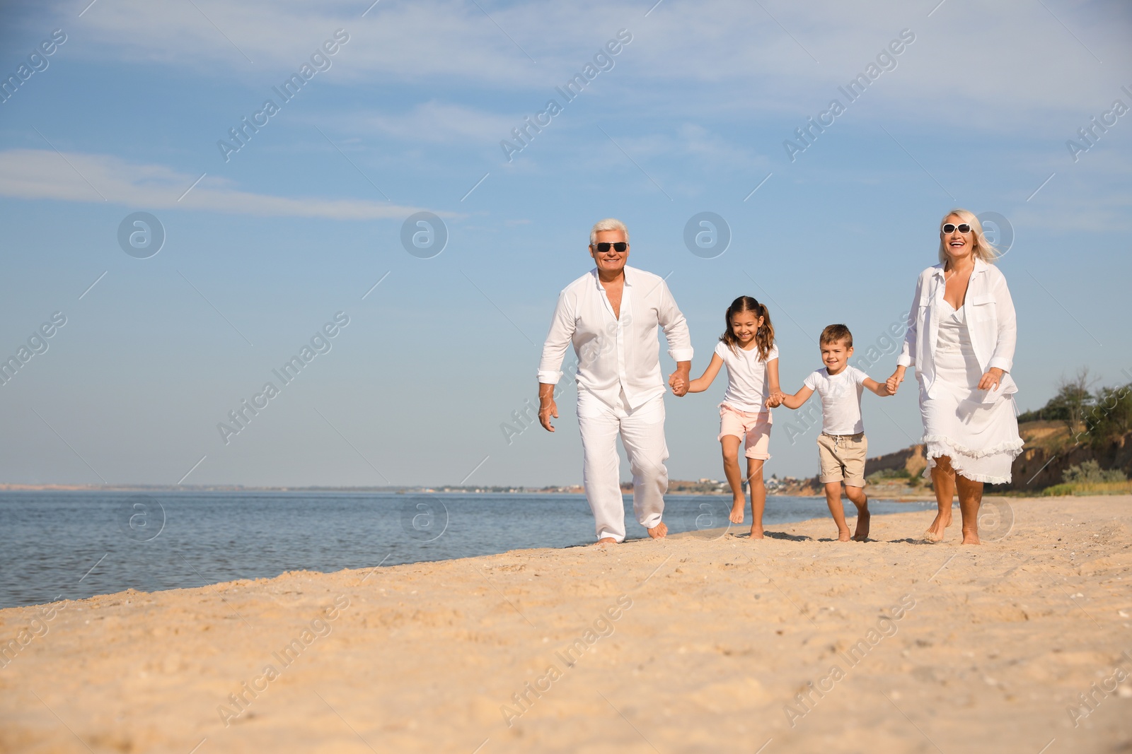 Photo of Cute little children with grandparents spending time together on sea beach