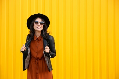 Photo of Beautiful young woman in stylish autumn clothes near yellow fence. Space for text
