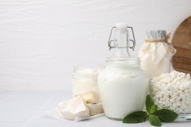 Different dairy products and mint on white table, space for text