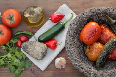 Ingredients for tasty salsa sauce, pestle and mortar on wooden table, flat lay