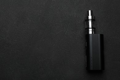 Electronic cigarette on black table, top view with space for text. Smoking alternative