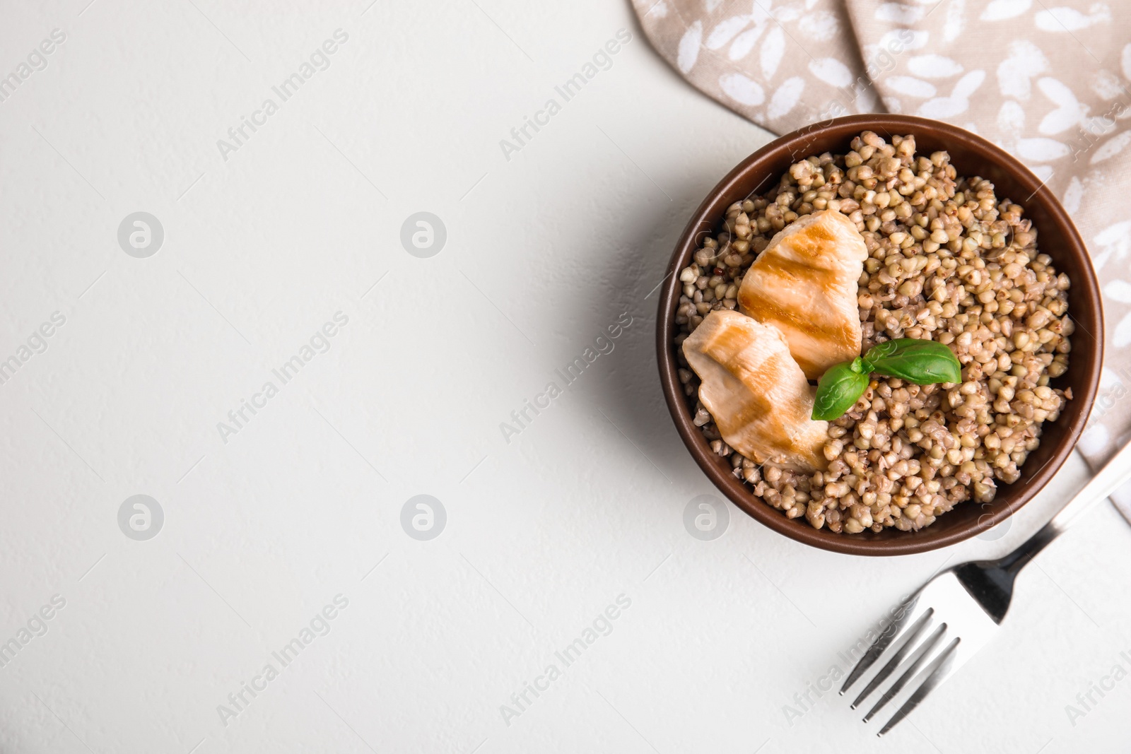 Photo of Tasty buckwheat porridge with meat on white table, flat lay. Space for text