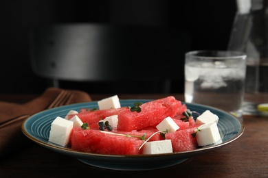 Photo of Delicious salad with watermelon and cheese on wooden table, closeup