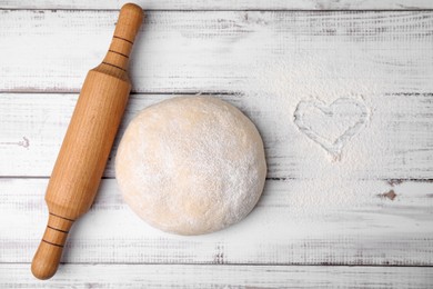 Photo of Fresh dough, rolling pin and flour on white wooden table, flat lay