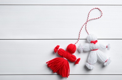 Photo of Traditional martisor shaped as man and woman on white wooden background, top view with space for text. Beginning of spring celebration
