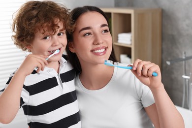 Photo of Mother and her son brushing teeth together in bathroom