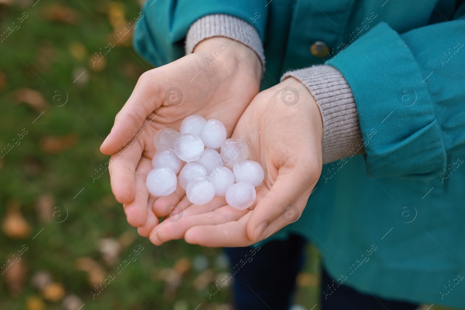 Photo of Woman holding hail grains after thunderstorm outdoors, closeup