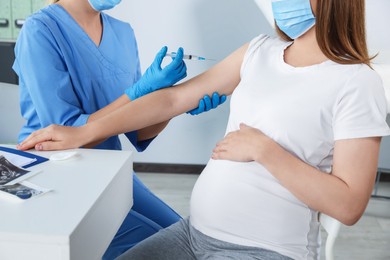 Photo of Doctor giving injection to pregnant woman in hospital, closeup