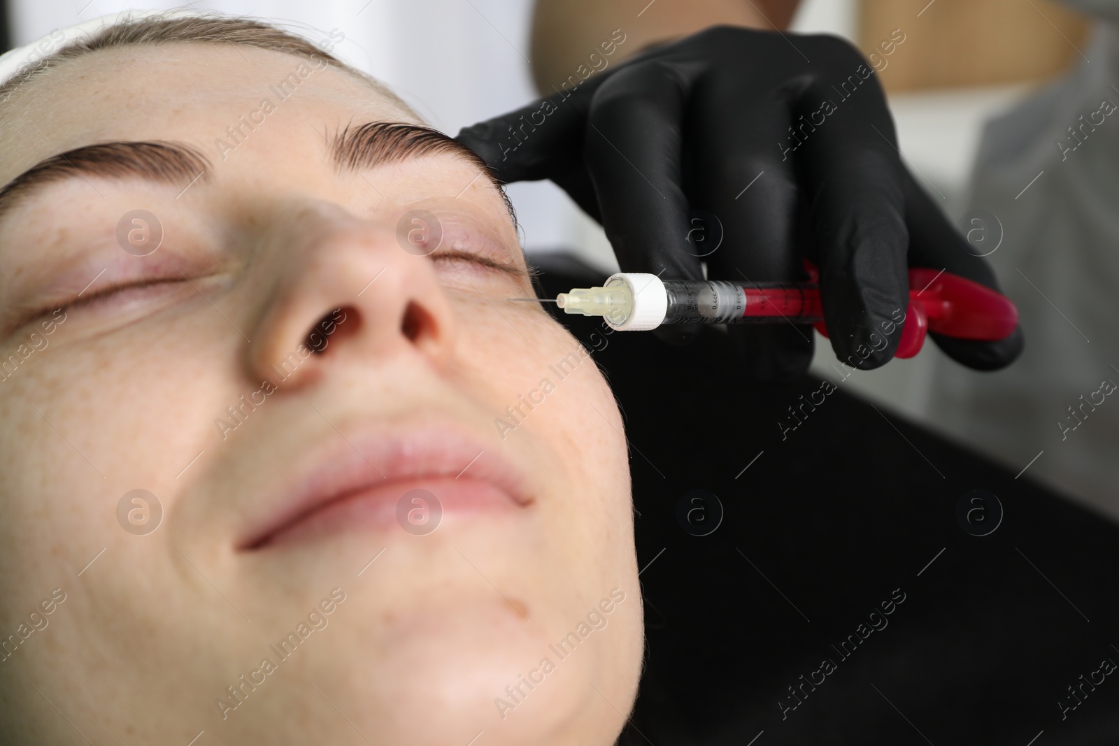 Photo of Cosmetologist giving facial injection to patient indoors, closeup. Cosmetic surgery