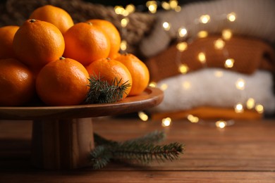 Photo of Stand with delicious ripe tangerines and fir twigs on wooden table. Space for text
