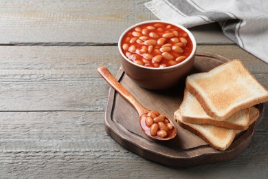 Photo of Toasts and delicious canned beans on wooden table, space for text