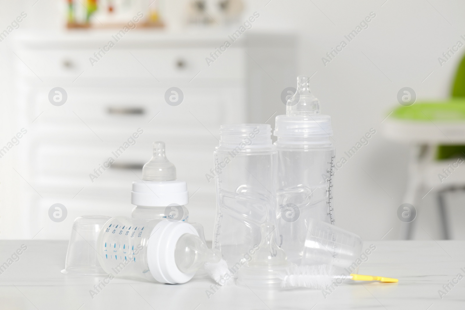 Photo of Clean baby bottles with nipples after sterilization and cleaning brush on white table indoors