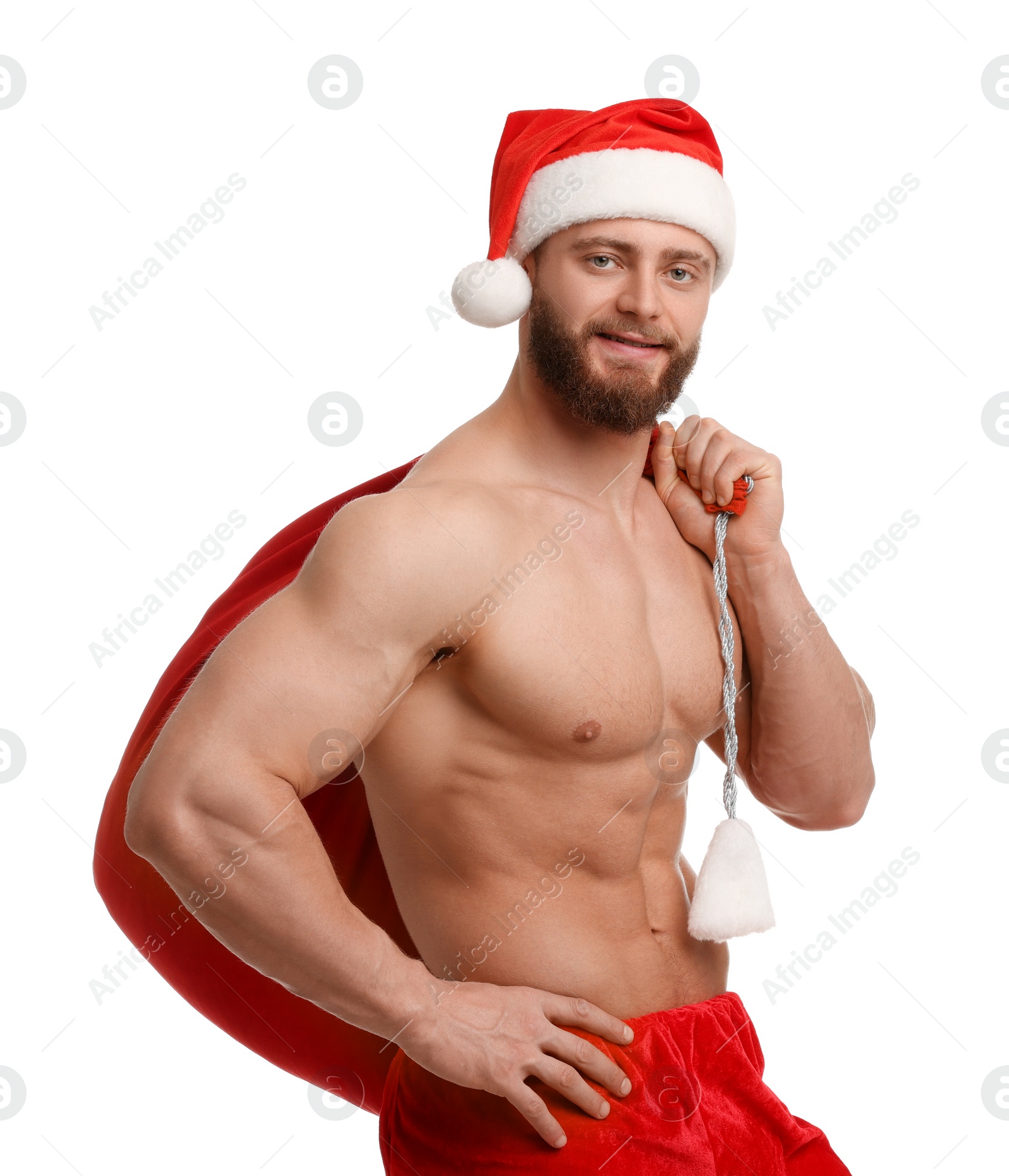 Photo of Muscular young man in Santa hat holding bag with presents on white background