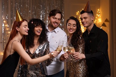 Photo of Happy friends clinking glasses of sparkling wine at birthday party indoors