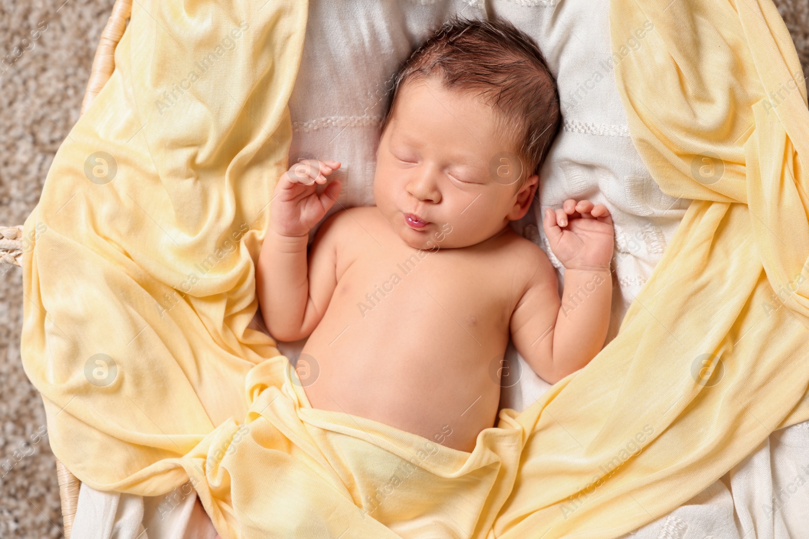 Photo of Cute newborn baby sleeping on white blanket in crib, top view