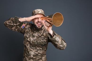 Military man with megaphone on gray background
