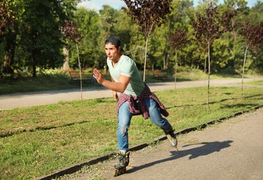 Photo of Handsome young man roller skating in park