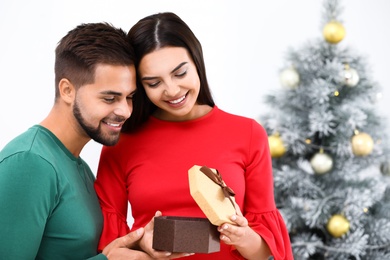 Happy young couple with Christmas gift at home