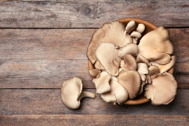 Bowl of delicious organic oyster mushrooms on wooden background, top view with space for text