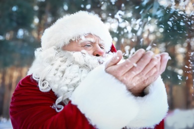 Photo of Happy Authentic Santa Claus blowing snow from his hands outdoors