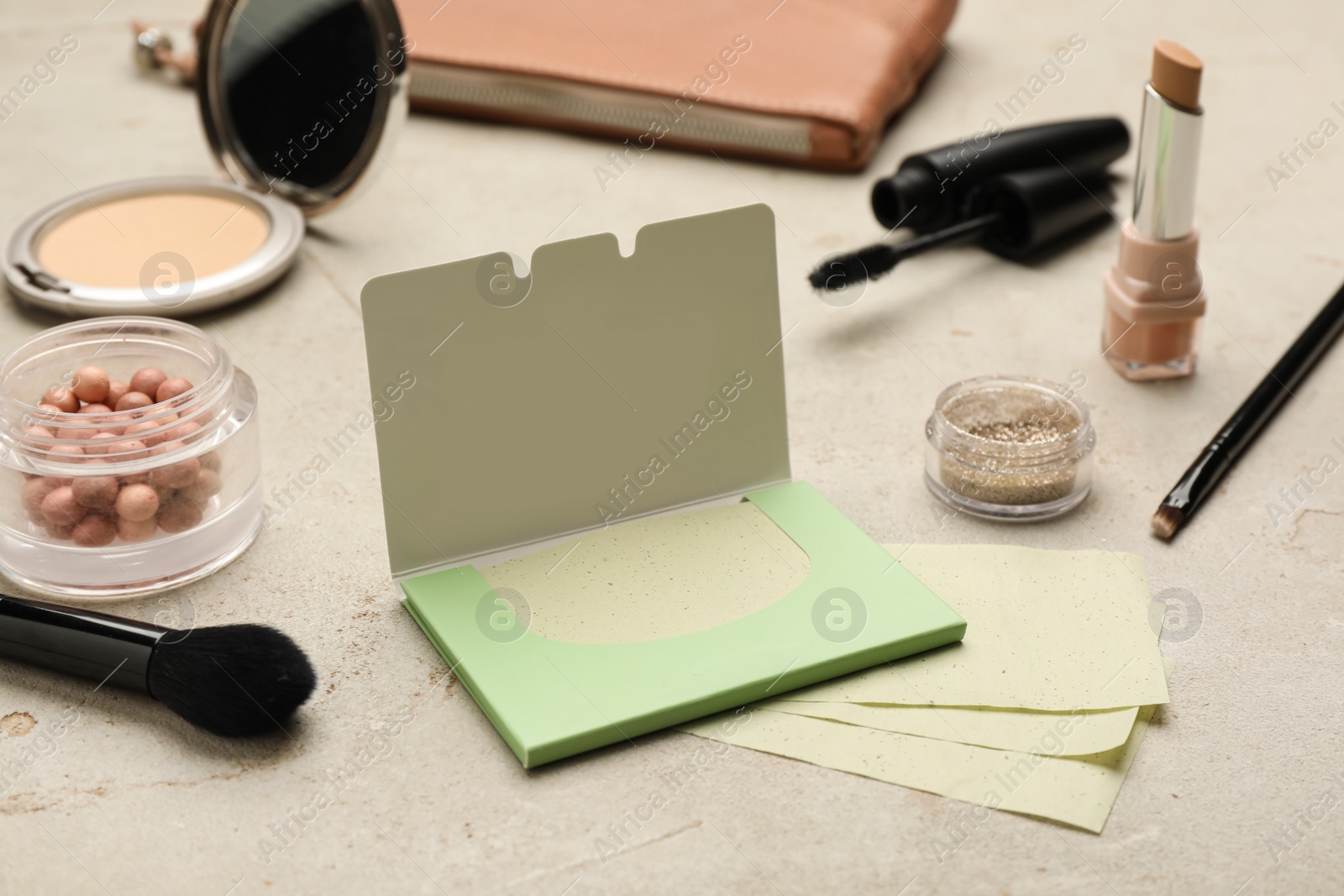 Photo of Facial oil blotting tissues and different decorative cosmetics on light grey background. Mattifying wipes