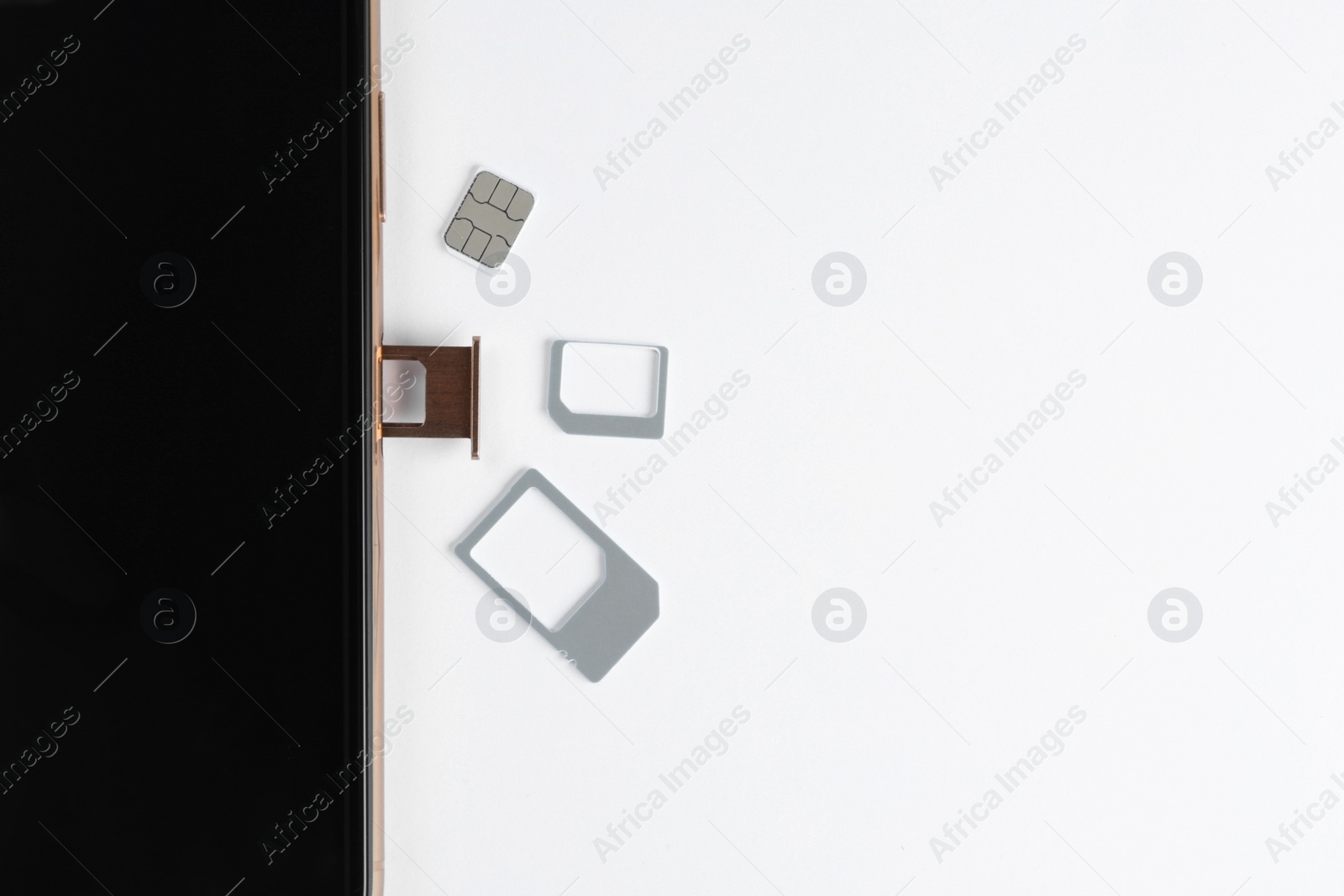 Photo of SIM card and mobile phone on white table, top view