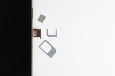 Photo of SIM card and mobile phone on white table, top view