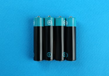 New AAA batteries on light blue background, flat lay