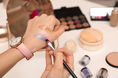 Photo of Beauty blogger doing eyeshadow swatches at table, closeup