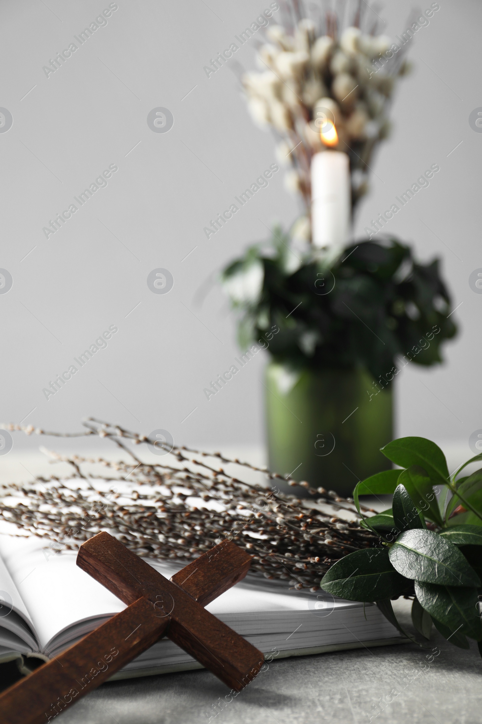 Photo of Bible, willow branches and wooden cross on grey table, closeup