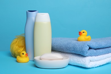 Photo of Baby cosmetic products, bath ducks, sponge and towels on light blue background