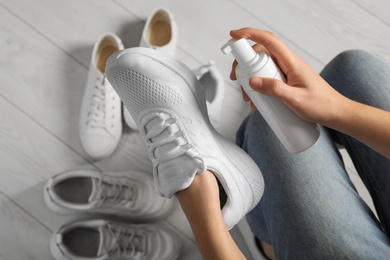 Woman cleaning stylish footwear indoors, closeup. Shoe care accessory