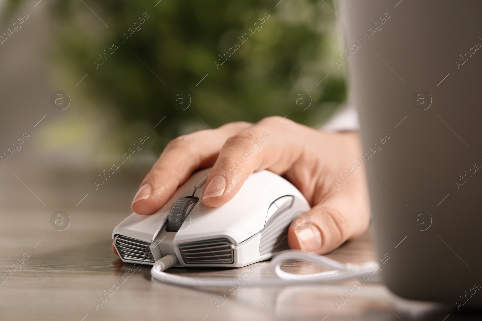 Photo of Woman using computer mouse with laptop at table, closeup