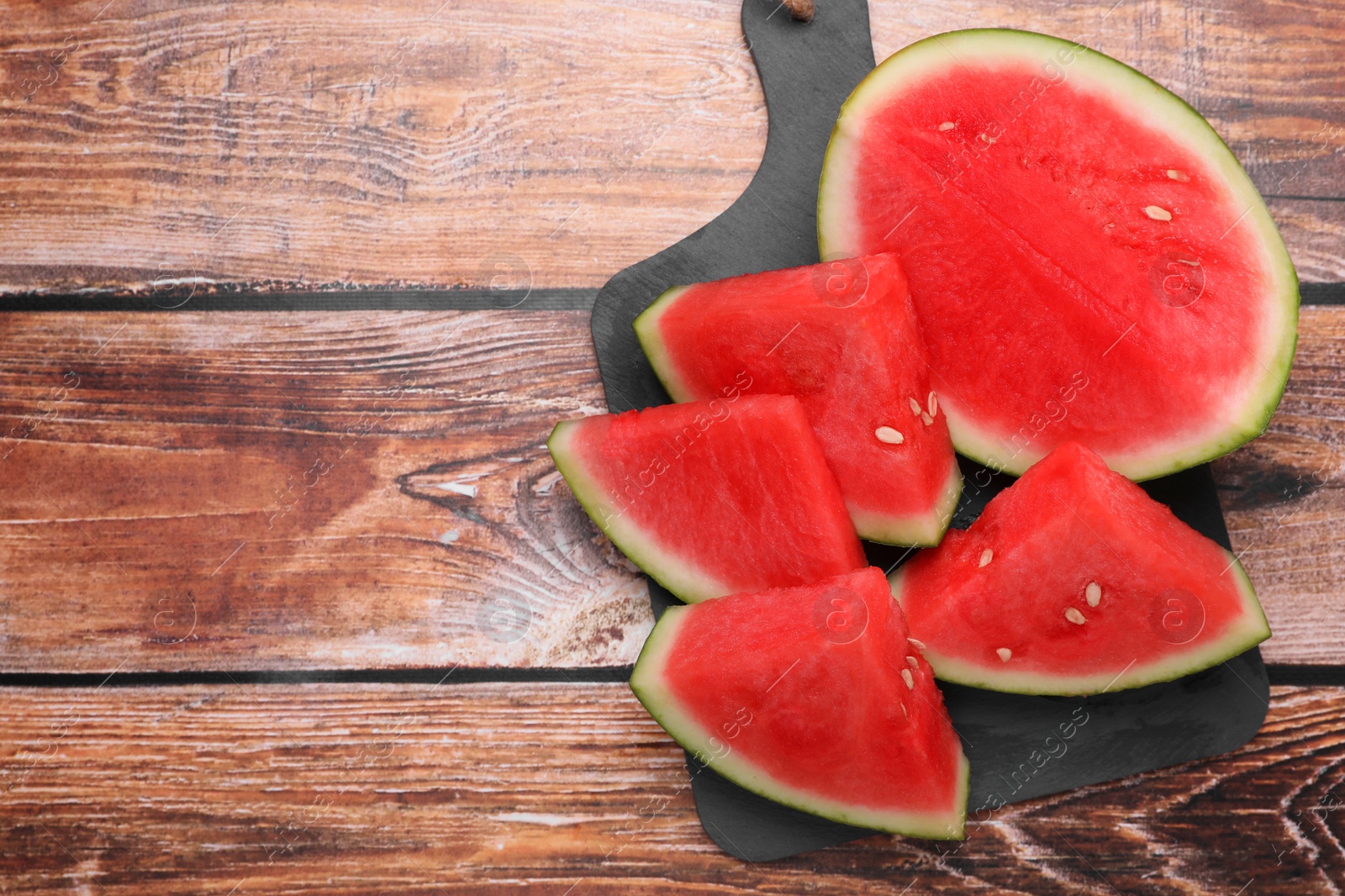 Photo of Juicy ripe cut watermelons on wooden table, top view. Space for text