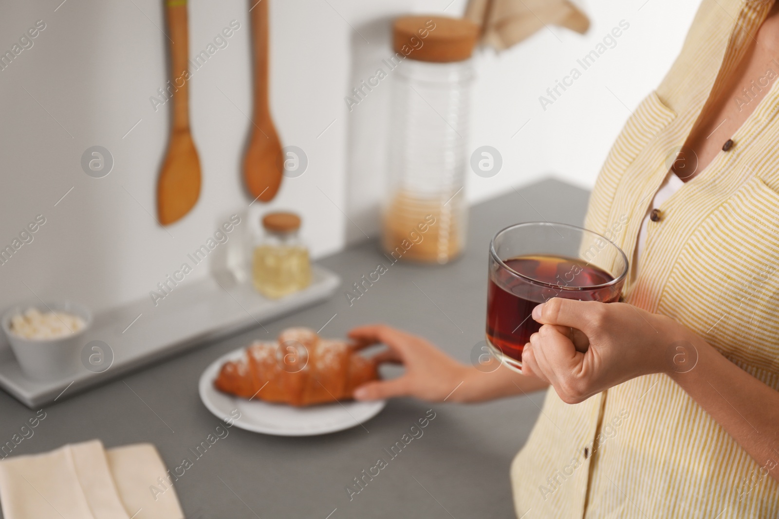 Photo of Woman holding glass cup of tea at home, closeup. Morning routine