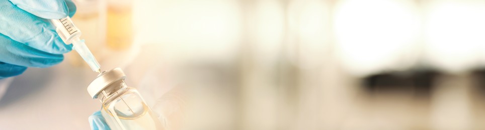 Image of Doctor filling syringe with medication from glass vial on blurred background, closeup. Banner design