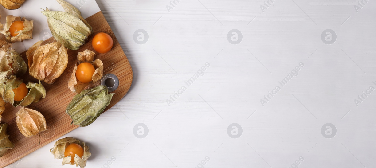 Image of Ripe physalis fruits on white wooden table, flat lay with space for text. Banner design