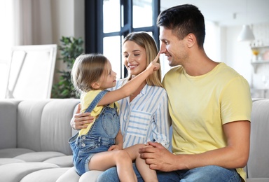 Happy family with little daughter on sofa in living room