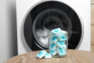 Photo of Jar with water softener tablets on wooden table near washing machine