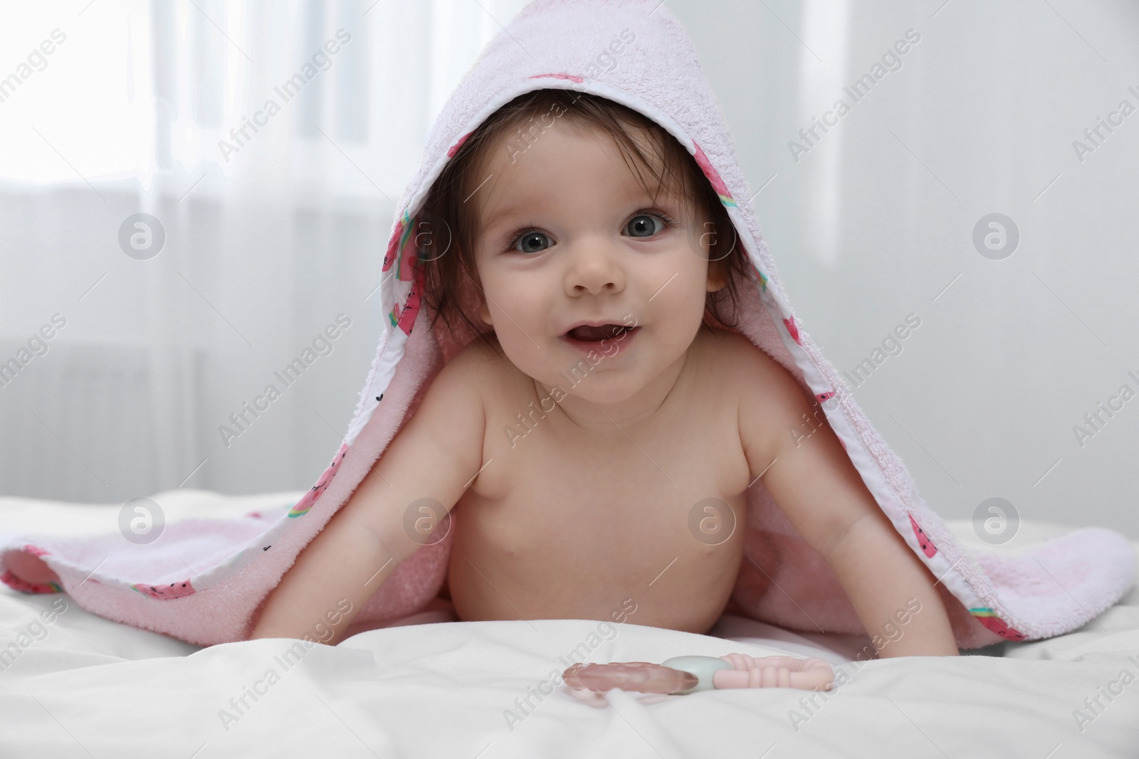 Photo of Cute little baby in hooded towel after bathing on bed at home