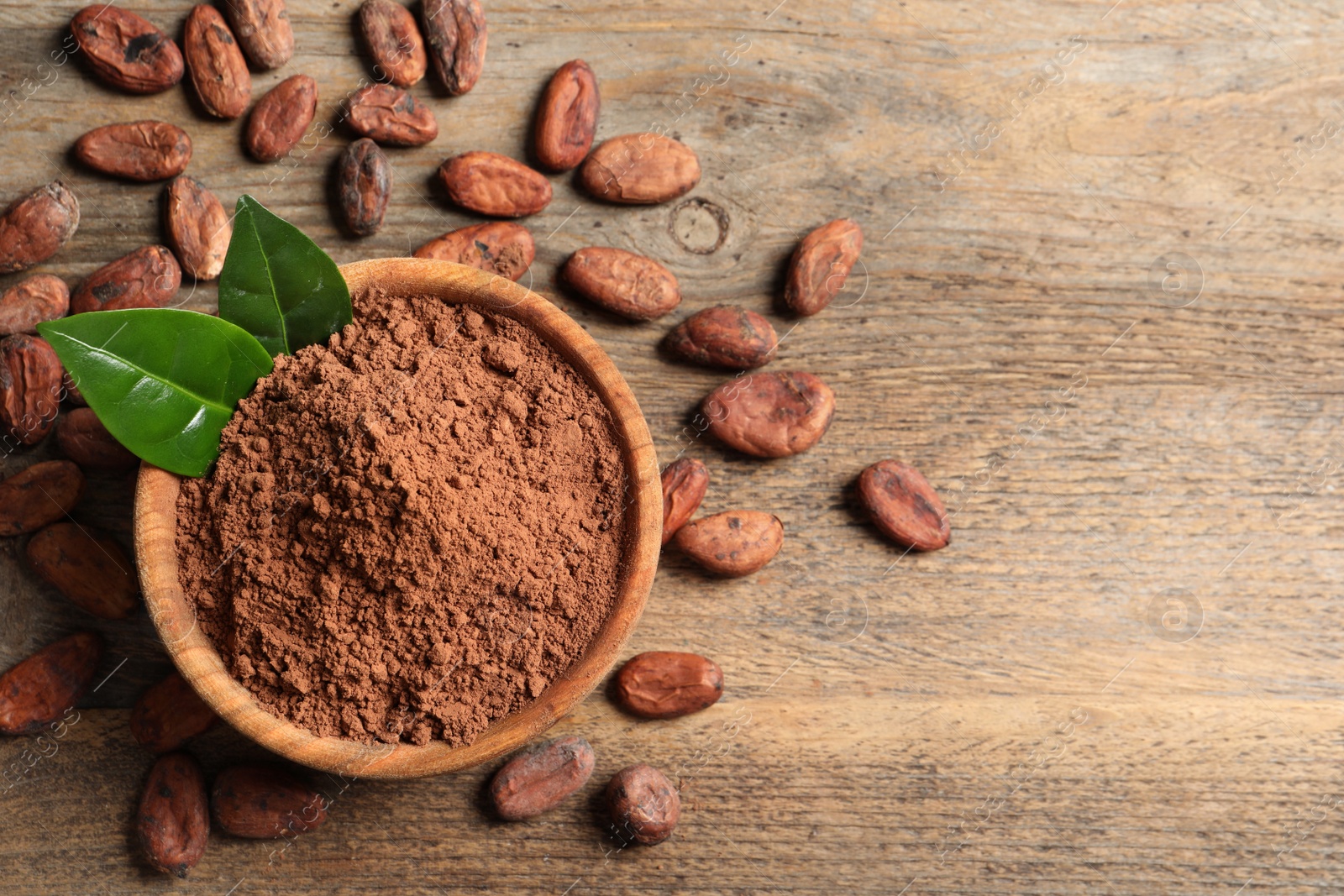 Photo of Bowl with cocoa powder on wooden table, top view. Space for text