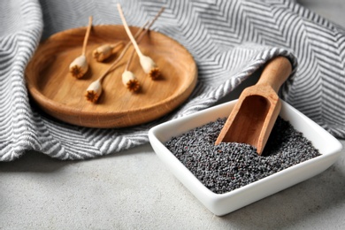 Bowl with scoop and poppy seeds on table