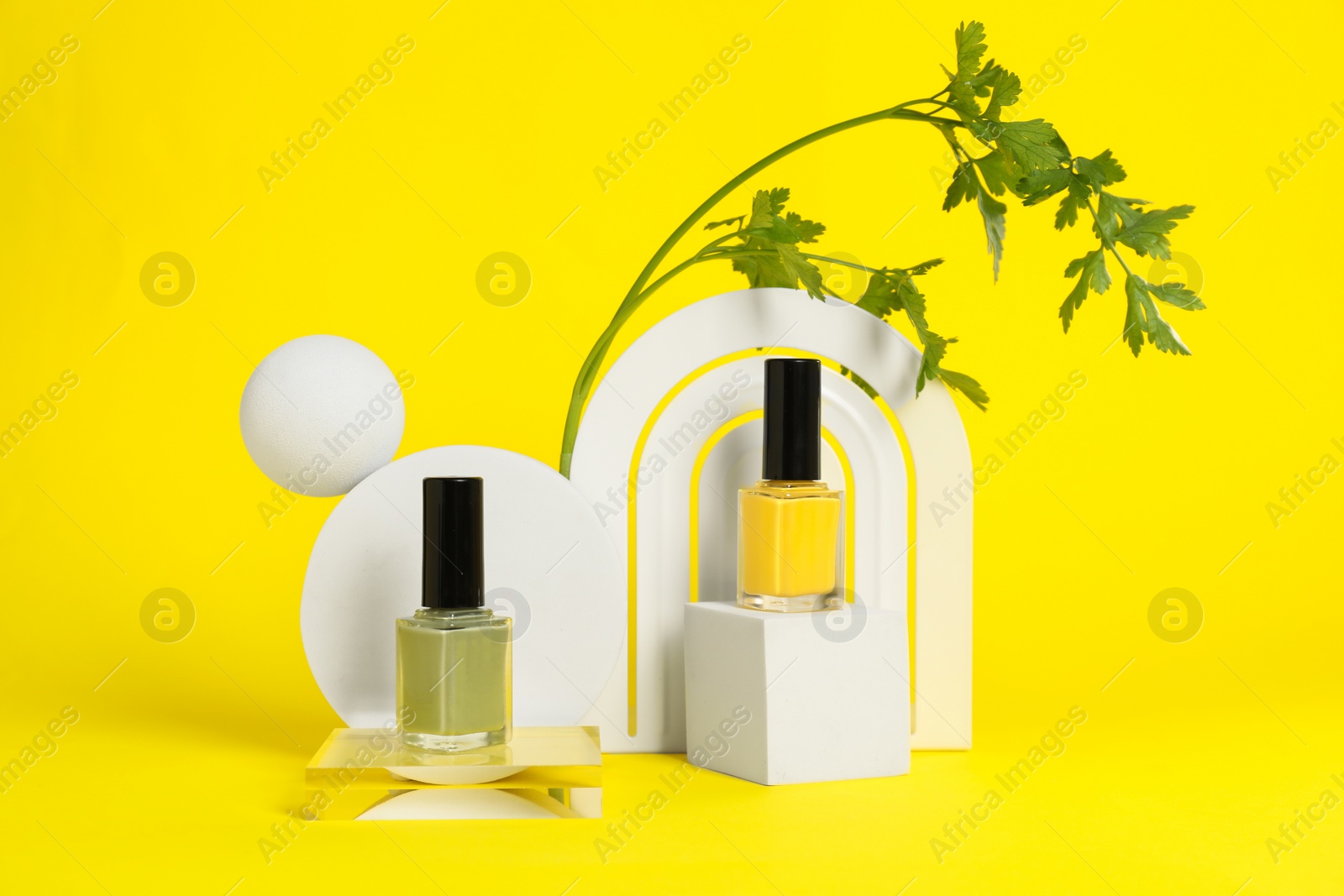 Photo of Stylish presentation of beautiful nail polishes in bottles on yellow background