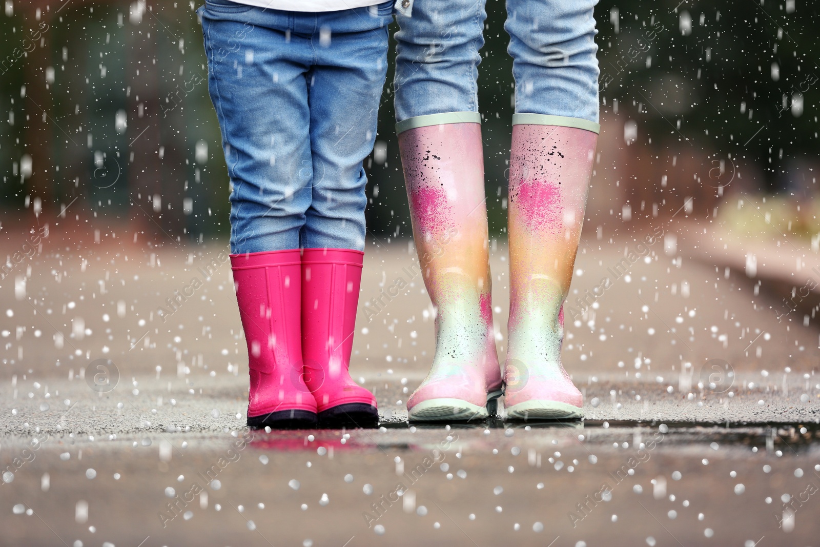 Image of Mother and daughter wearing rubber boots on rainy day with hail, closeup