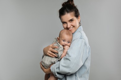 Photo of Beautiful mother with her cute baby on grey background. Space for text